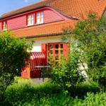 Rotes Haus mit Terrasse und Garten. Rote Fenster und Tür. Strukturierte Dachziegel.