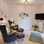 Wohnzimmer mit zwei Sesseln, Fernseher und Pflanze.