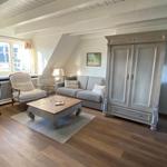 Wohnzimmer mit Sofa, Sessel, Kamin und Holzboden.