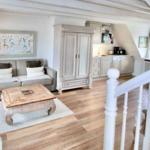 Wohnbereich mit Sofa, Couchtisch und Küchenbereich unter Dachschräge.