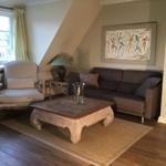 Wohnzimmer mit Sofa, Sessel und Holztisch unter Dachschräge.