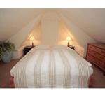 Schlafzimmer mit Doppelbett, Nachttischen und Schrank unter schrägen Dachbalken.