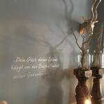 Wand mit Zitat, Rehgeweih und Zweige in Gläsern auf Holzständern