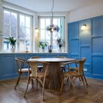 Esszimmer mit blauen Wänden, Holzboden und runden Tisch mit Stühlen.