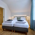 Schlafzimmer mit Doppelbett, Fenster und Kleiderschrank.