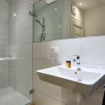 Bad mit Dusche, Waschbecken und Spiegel