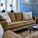 Ein Wohnzimmer mit braunem Sofa, dekorativen Kissen und blauen Wänden.