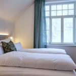 Schlafzimmer mit Bett, Fenster und Vorhängen.