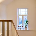 Hausflur mit Treppe, Fenster und Pflanzen auf dem Fensterbrett.