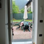 Durch die Tür ist eine Terrasse mit Tisch, Stühlen und einem geschlossenen Sonnenschirm zu sehen.