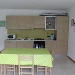 Küche mit Essbereich, grüner Tischdecke und Holzmöbel.