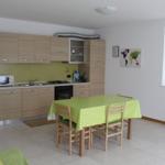 Küche mit Essbereich, grüner Tischdecke und Holzstühlen