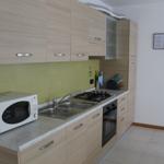 Küche mit Holzschränken, Mikrowelle, Spüle und Kochfeld.