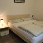 Schlafzimmer mit Doppelbett, Nachttisch und Wandbildern.