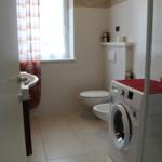 Badezimmer mit Waschmaschine, Toilette und Dusche.