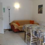 Wohn- und Essbereich mit Sofa, Tisch und Stühlen. Wandlampen und Wandbild.