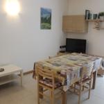 Esszimmer mit Tisch, Stühlen und Fernseher. Wandregale und Bild an der Wand.