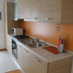 Küche mit Holzschränken, Edelstahlspüle und Mikrowelle.