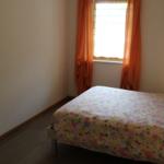 Schlafzimmer mit Bett, Fenster und Spiegel an der Wand.