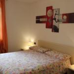 Schlafzimmer mit Bett, Nachttischen und Wandbildern.