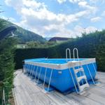 Blauer Aufstellpool auf Terrasse mit Blick auf grüne Hänge.