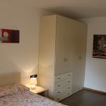 Schlafzimmer mit Bett, Kleiderschrank und Wandbildern.