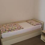 Ein Bett mit buntem Deckenbezug und Nachttisch mit Lampe.