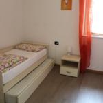 Ein Schlafzimmer mit einem Bett, einem Nachttisch und einem Fenster mit orangefarbenen Vorhängen.