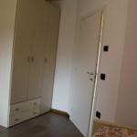 Schlafzimmer mit Kleiderschrank, Tür und Bett mit gemusterter Bettdecke.