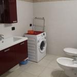 Badezimmer mit Waschmaschine, Toilette und Bidet. Rot lackierte Schränke und Spiegelschrank.