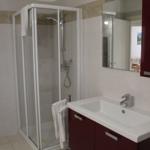 Bad mit Dusche, Waschbecken und Spiegel.