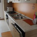 Küche mit Arbeitsplatte, Spüle, Herd und Mikrowelle.