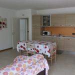 Küche mit Essbereich und Schlafplatz mit floralen Tischdecken.