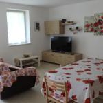 Wohn- und Essbereich mit Sofa, TV und Esstisch mit Blumentischdecke.