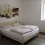 Schlafzimmer mit Bett, Nachttisch und Wandbild mit Lilien.