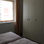 Schlafzimmer mit Bett, Kleiderschrank und Fenster mit Jalousie und Vorhang.