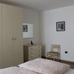 Schlafzimmer mit Bett, Kleiderschrank, Schreibtisch und Stuhl.