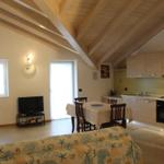 Wohnküche mit Holzbalkendecke, Esstisch, Sofa und TV.