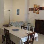 Essbereich mit Tisch, Stühlen und Sofa. Wanddekoration und Schrank sind sichtbar.