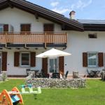 Haus mit Balkon, Terrasse und Spielplatz im Garten.