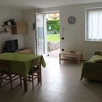 Wohn- und Essbereich mit grünem Tischdecken und Sofa, Tür zum Garten.