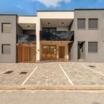 Modern villa with wooden railings and paved parking lot.