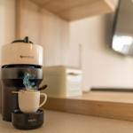 Nespresso coffee machine with steaming cup on kitchen counter