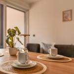 Dining table with steaming cups, plant, and seating in the background.