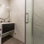 Bathroom with shower, washing machine, and sink.