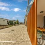Terrace with wooden table and chairs beside a modern building.
