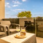 Terrace with seating and drinks. Glass railing and view of tree.