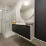 Bathroom with shower, sink and toilet. Black and white marble tiles.