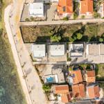 Aerial view of houses by the sea with a swimming pool and roads.
