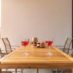 Wooden table with two glasses and chairs in the outdoor area.